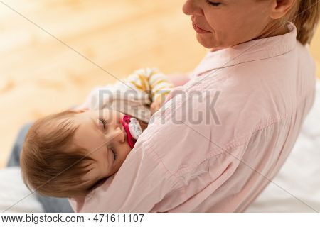 Loving Mother Holding Her Little Sleeping Baby Girl On Hands, Comforting Infant Kid And Looking At C