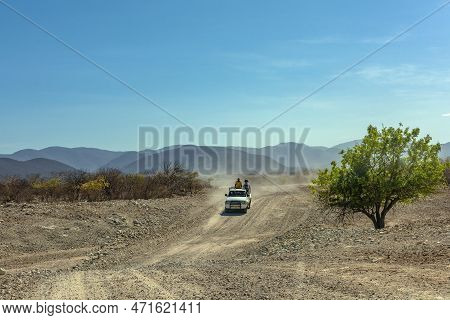 Car On A Dusty Gravel Road Along The Kunene River In Northern Namibia