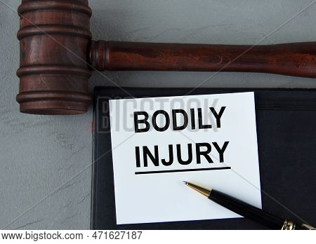 Bodily Injury - Words On A White Sheet With Leather Notebooks, A Judge's Hammer And A Pen