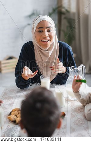 Smiling African American Mother In Hijab Talking To Kids During Suhur Breakfast At Home.