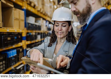 Managers In Suit Controlling Goods In A Waehouse.