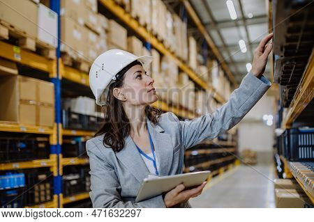 Manager Woman In Suit Controlling Goods In A Waehouse.