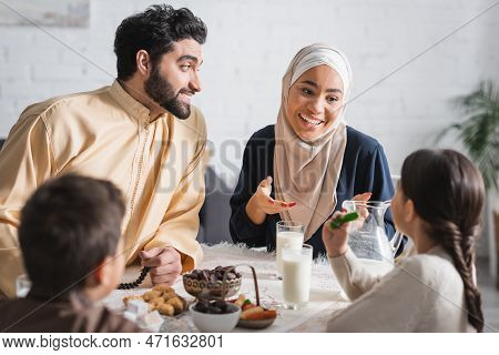 Positive Muslim Family Talking To Kids During Suhur Breakfast At Home.