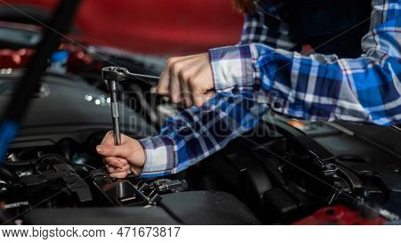 Female Auto Mechanic Unscrewing A Nut To Replace A Car Spark Plug.