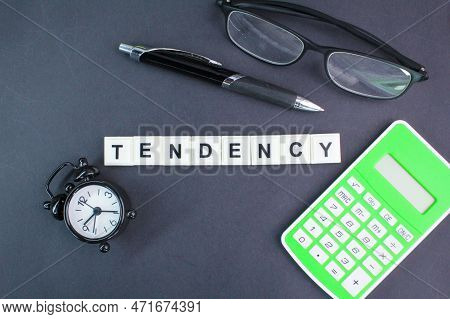 Calculator, Alarm Clock, Glasses And Pen With The Word Tendency. The Concept Of Tendency Of Somethin