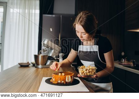 Confectioner Decorates With Berries A Biscuit Cake With White Cream And Chocolate. Cake Stands On A
