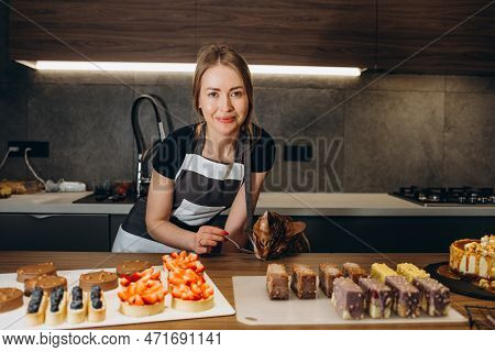 The Cat In The Apron Is Eating Dough In The Kitchen. Close-up