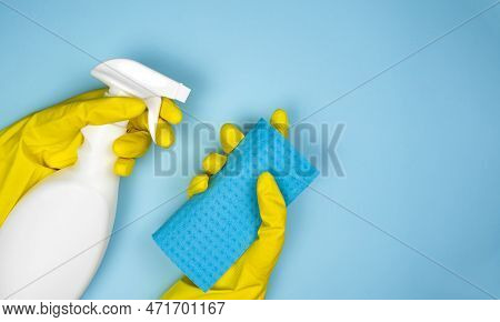 Woman's Hands In Rubber Gloves Hold A Cleaner And Rag On A Blue Background. Housekeeping Concept. Cl