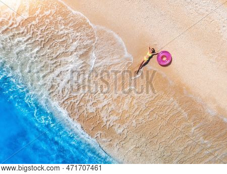 Aerial View Of Young Woman With Pink Swim Ring On The Sandy Beac