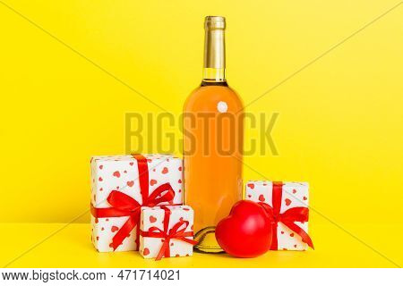 Bottle Of Wine On Colored Background For Valentine Day With Gift Box. Heart Shaped With Presrnt Box 