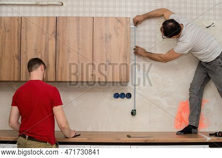 Two Craftsmen, Furniture Makers And Assemblers, Are Installing A Modern Kitchen In A Home, Tools In 