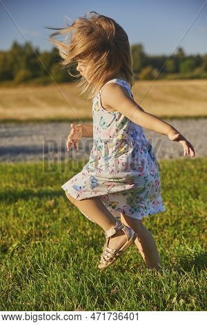 Charming Child In A Sundress Running Down The Street In The Suburbs