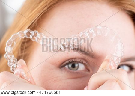 Dental Care.smiling Girl With Red Hair Holding Heart Shaped Aligners