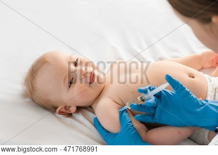 Doctor Vaccinating Smiling Baby In Clinic. One Year Little Baby Get An Injection. Pediatrician And P