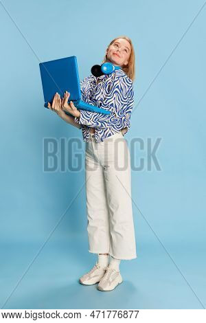 Full-length Portrait Of Cute Smiling Girl With Laptop Over Blue Studio Background. Happy Employee, S