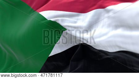 Detail Of The Sudan National Flag Waving In The Wind. Red, White, Black Horizontal Stripes With A Gr