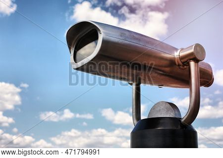 Steel Binoculars Over Blue Sky And Clouds