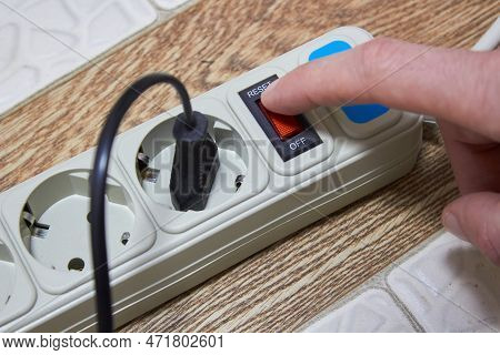 Finger Pressing The Button On The Electric Extension Cord