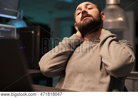 Tired Male Coder Dealing With Back Pain And Pressure, Working Late At Night And Feeling Tense. Exhau