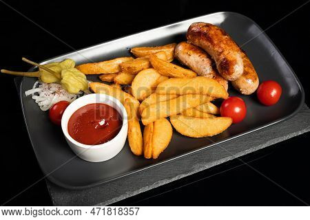 Delicious Juicy Kupaty Sausages Lie In A Plate With Potatoes, Sauce And Pepper. Top View