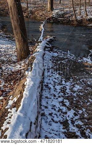 Hammel Creek Flows Through A Winter Forest And Under A Dead Snow Dusted Tree Fallen Across The Creek