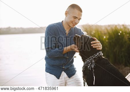 Man With Rotweiller Dog Playing Together Near The Lake