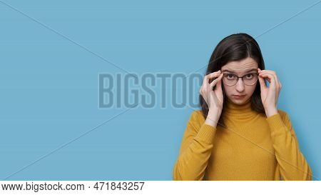 A Smiling Teenage Student Girl Taking Off Or Putting On Glasses On A Blue Background. Girl Sees Bett
