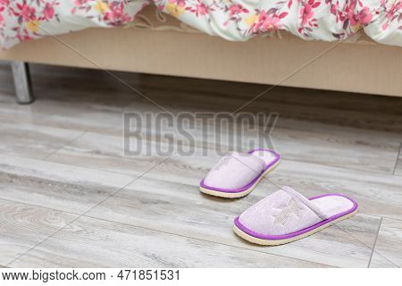 Slippers Near The Bed On Which The Person Sleeps. Morning At Home. House Slippers Scattered Near The