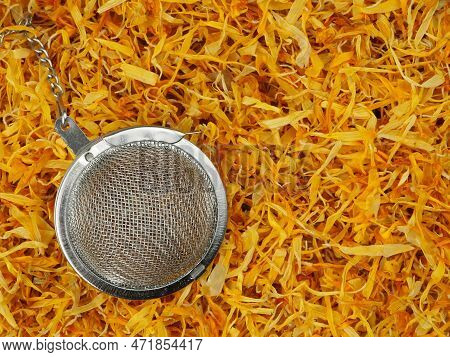 Close-up Of Orange Dried Marigold Petals As Background And Tea Strainer, Top View. Selective Focus.