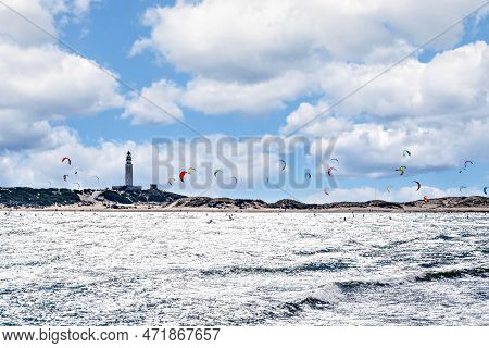 People Practicing Kitesurfing On The Beach Of Los Caños De Meca, Next To The Trafalgar Lighthouse, B