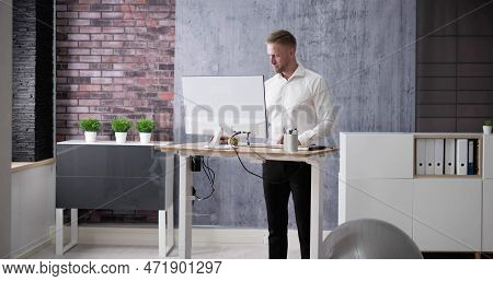 Man Using Adjustable Height Standing Desk In Office For Good Posture