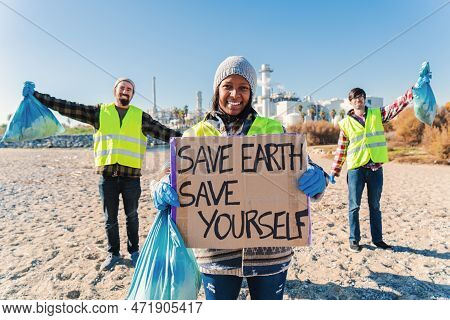 On Foreground One Happy Environmental Volunteer Smiling And Holding A Poster Cardboard With Positive