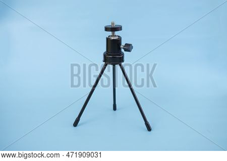 Black Mini Tripod With Steel Case And Ballhead Isolated On Blue Background.