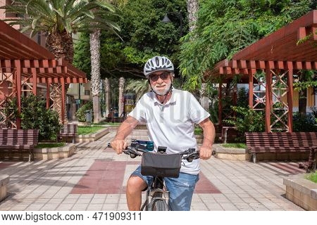 Portrait Of Smiling Senior Cyclist Man Wearing Helmet Running With Electric Bicycle In City Public P