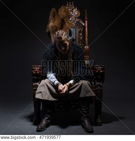 An Authoritative, Self-confident Woman In A Viking-style Fantasy Costume, Sitting On A High Chair Or