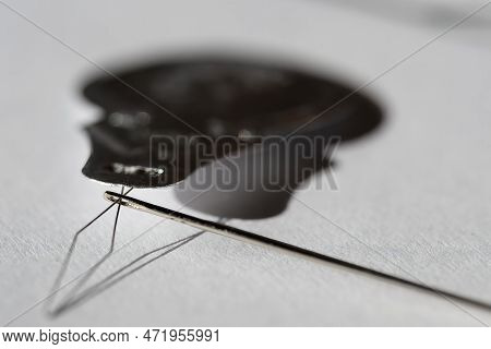 Sewing Needle Threader Tool In Use And A Single Black String.