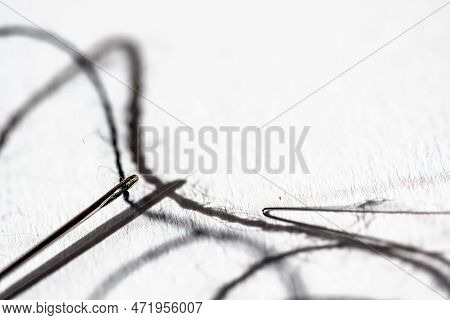 Sewing Needle Threader Tool In Use And A Single Black String.