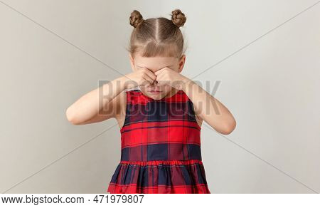 Child Holding Fists On Eyes Because Of Crying Offended Or Scratching Because Of Allergy On Grey Back