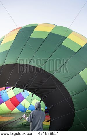 Colorful Hot Air Balloon On Ground Ready To Go To Sky. Person Staying Next To Big Hot Air Balloon An