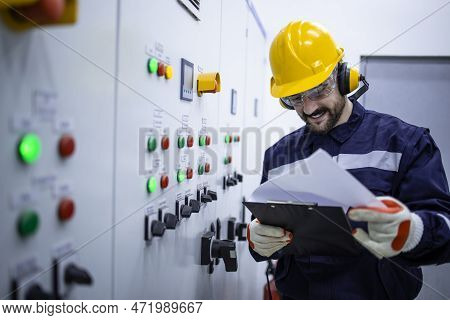 Electrical Engineer Reading Electric Scheme And Installations In Factory.