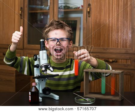 Exited boy with a microscope and colorful flasks.