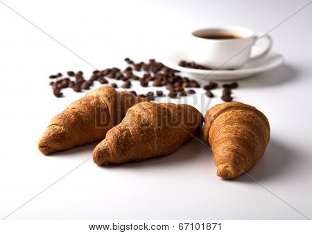 Three Croissant And A Cup Of Coffee With Coffee Beans