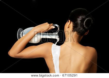 Nude woman is holding a ewer or yug of milk. Spa concept.