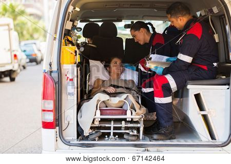 caring paramedic talking to patient in ambulance