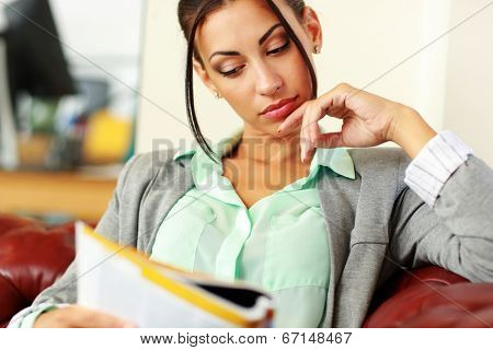 Businesswoman reading magazine in modern office