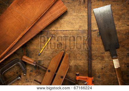 Wood working. Saw, clamps and mahogany planks on a work desk under incandescent light. 