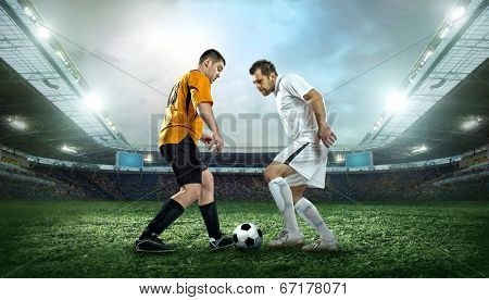 Two football players with ball in action outdoors.