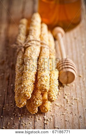 bread sticks grissini with sesame seeds and honey on rustick wooden board