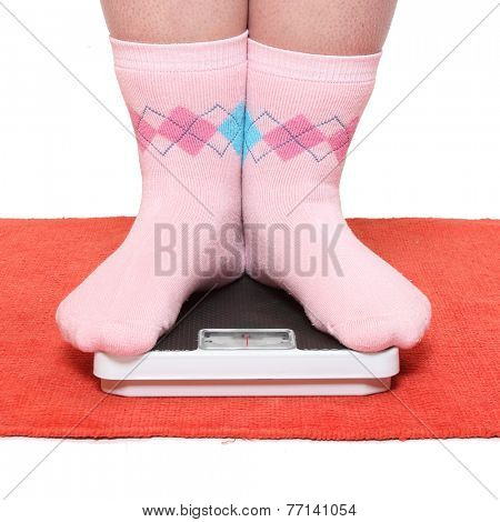 Overweight woman in funny socks standing on a weighing machine.