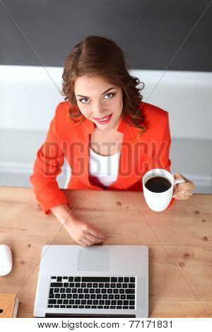 Attractive woman sitting at desk in office, working with laptop